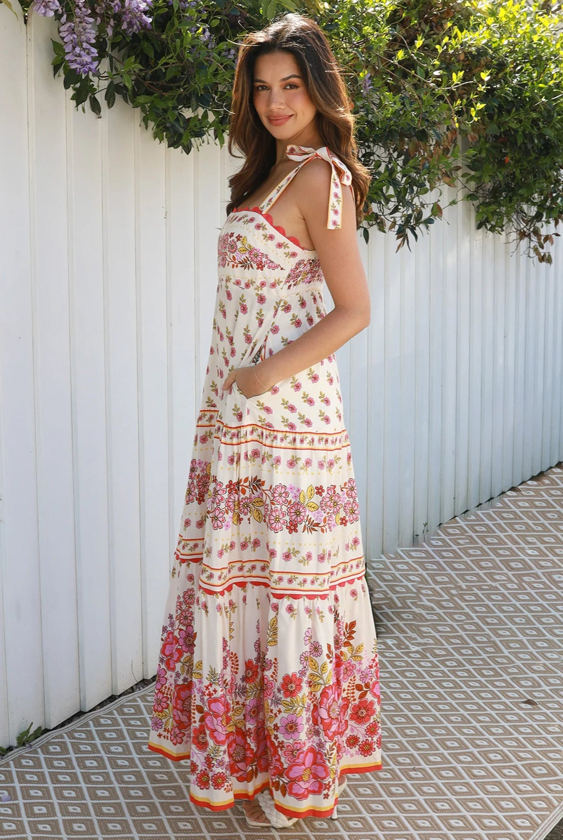 Cream rayon boho maxi dress with blush and rose floral print, tie shoulders, lace trim, and border hemline — Love at First Bloom
