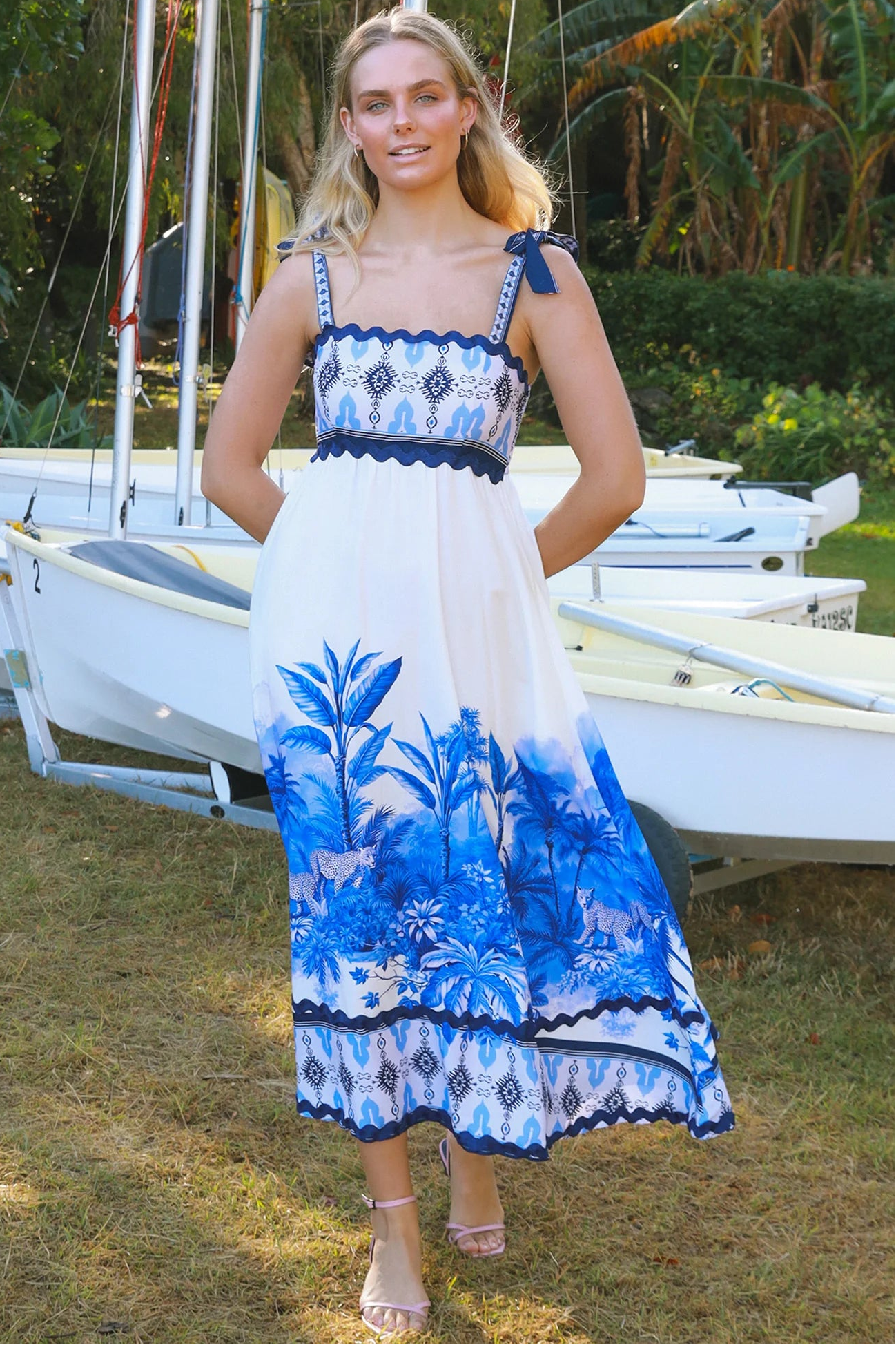 Model wearing blue-white Salty Palm maxi dress with tie straps and border print, light summer aesthetic for warm-weather days.