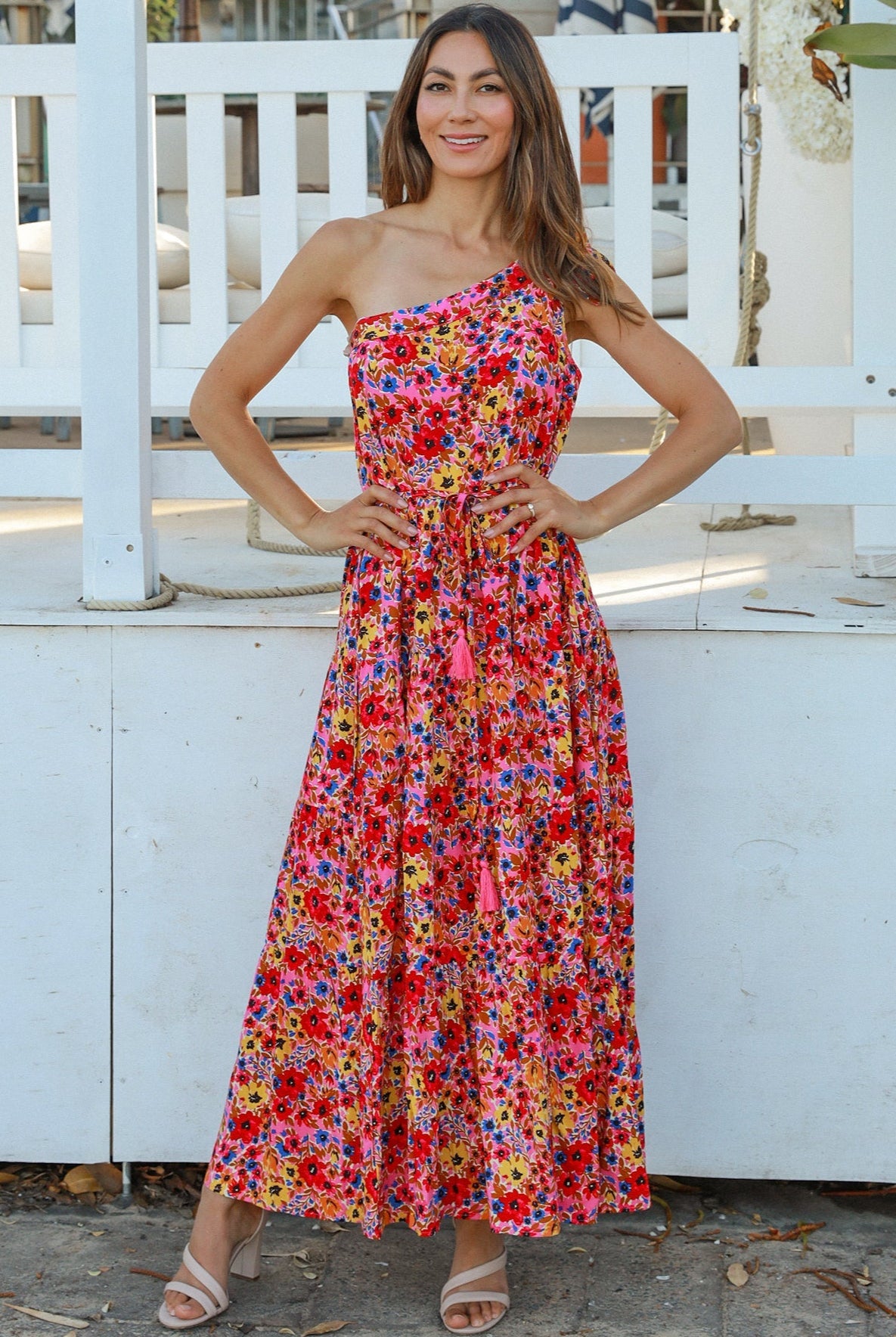 Women wearing a one-shoulder floral boho maxi dress with tassel waist tie - Lyric dress Australian summer fashion.