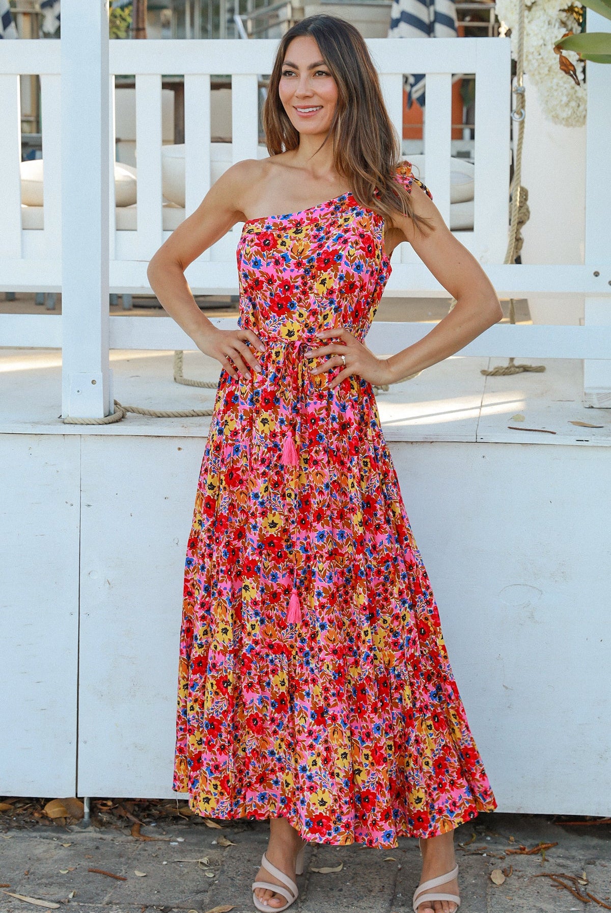 Women wearing a one-shoulder floral boho maxi dress with tassel waist tie - Lyric dress Australian summer fashion.