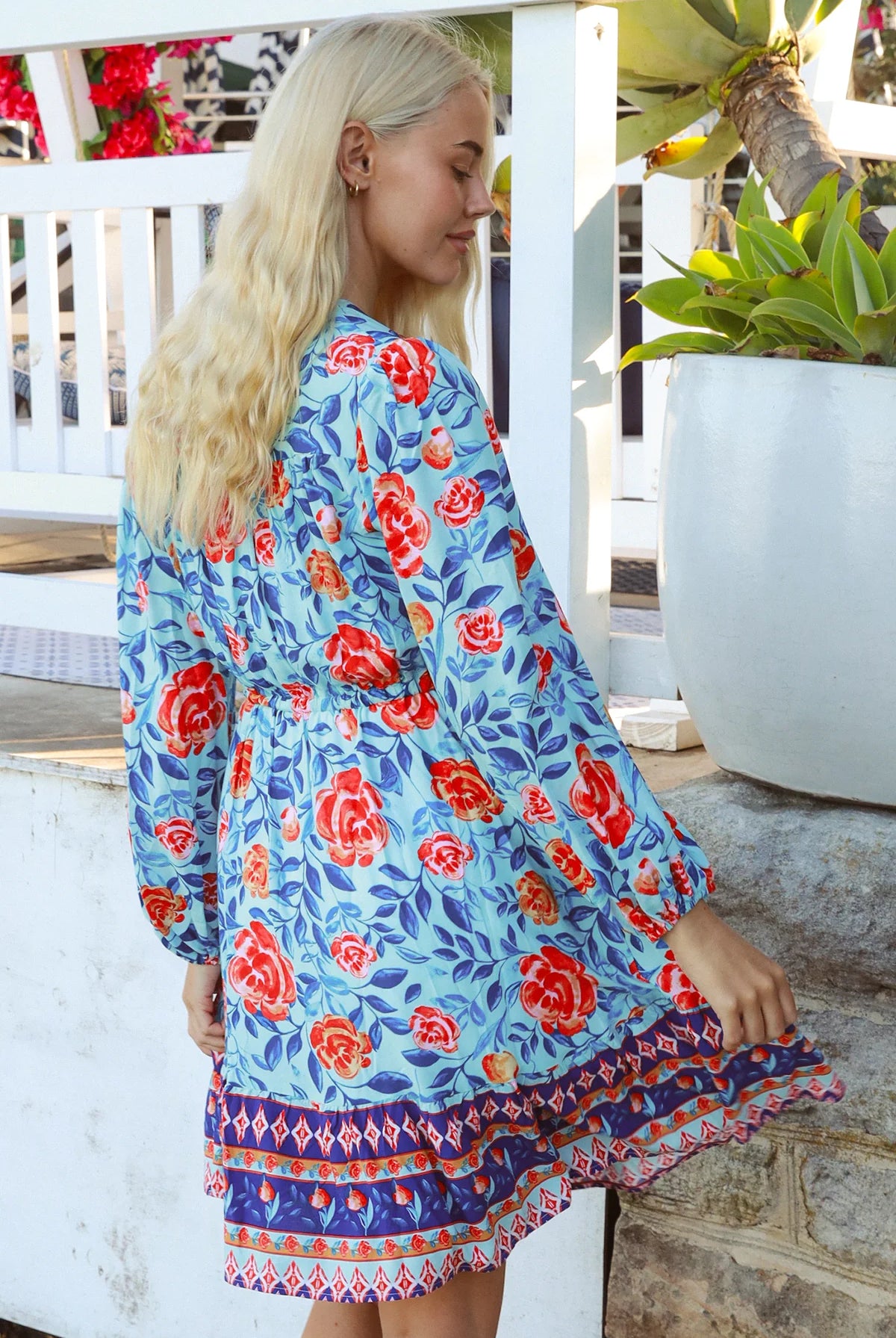 Blonde woman in blue floral boho mini dress with red roses and border print details - Clarice Rose Mini Dress Bohemian Love Runway.