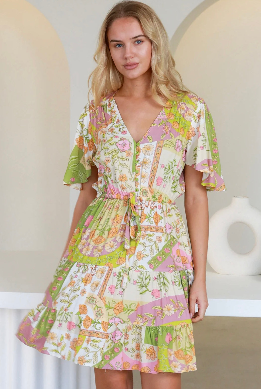 “Woman in vintage floral patchwork mini dress with flutter sleeves and drawstring waist – boho dresses Australia”
