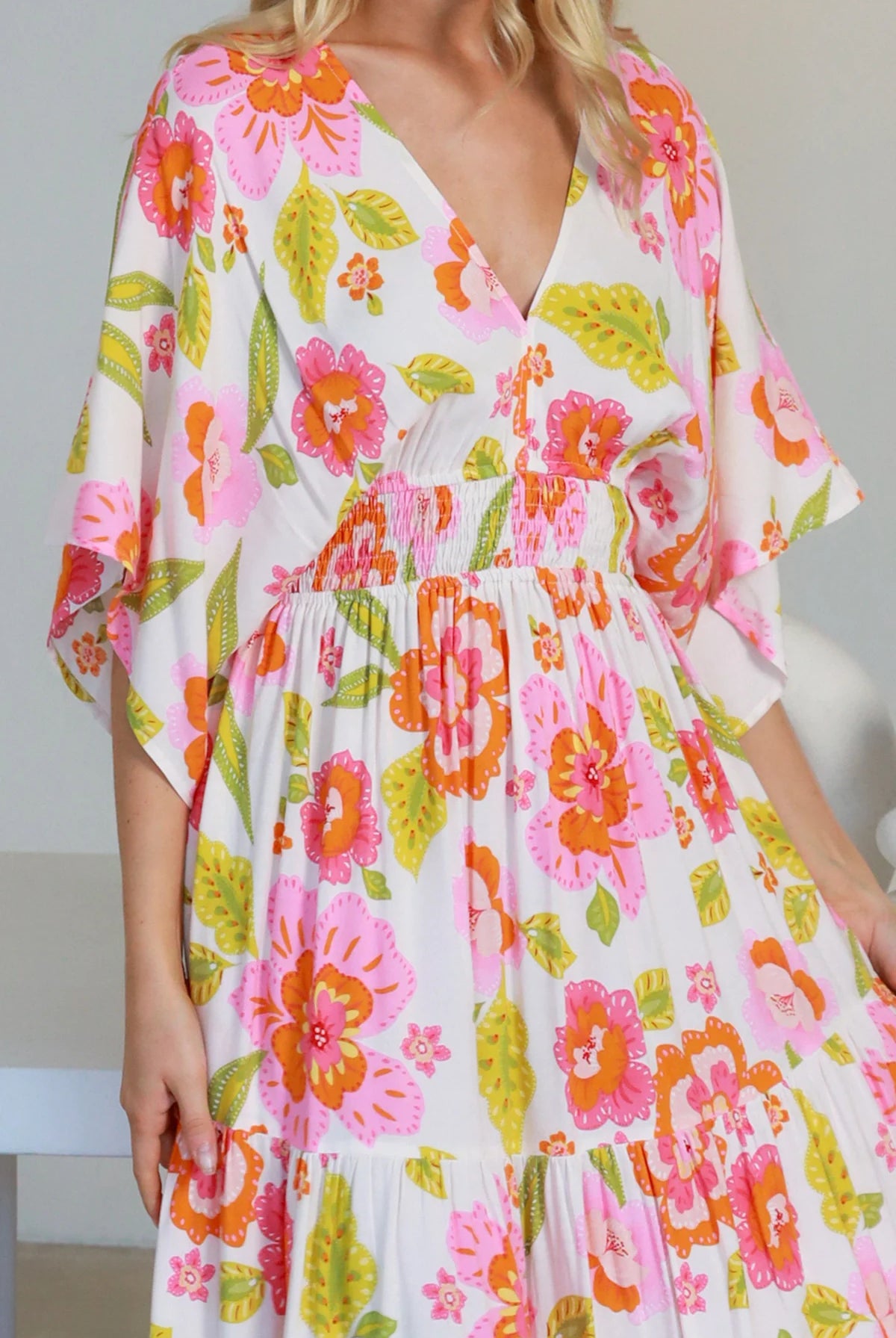 Woman in a coral-pink floral boho maxi dress with kimono sleeves - Isla Grace Tiered Maxi Dress Australia.