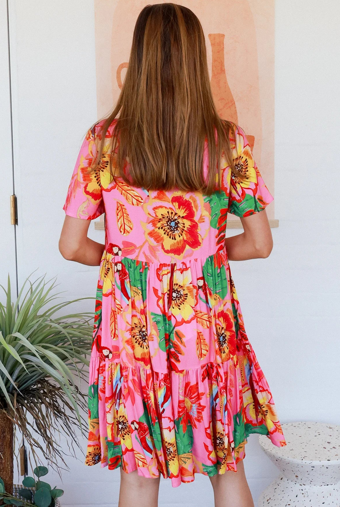 Pink floral mini dress with poppy and parrot print, V-neck button bodice, tassel ties and flutter sleeves