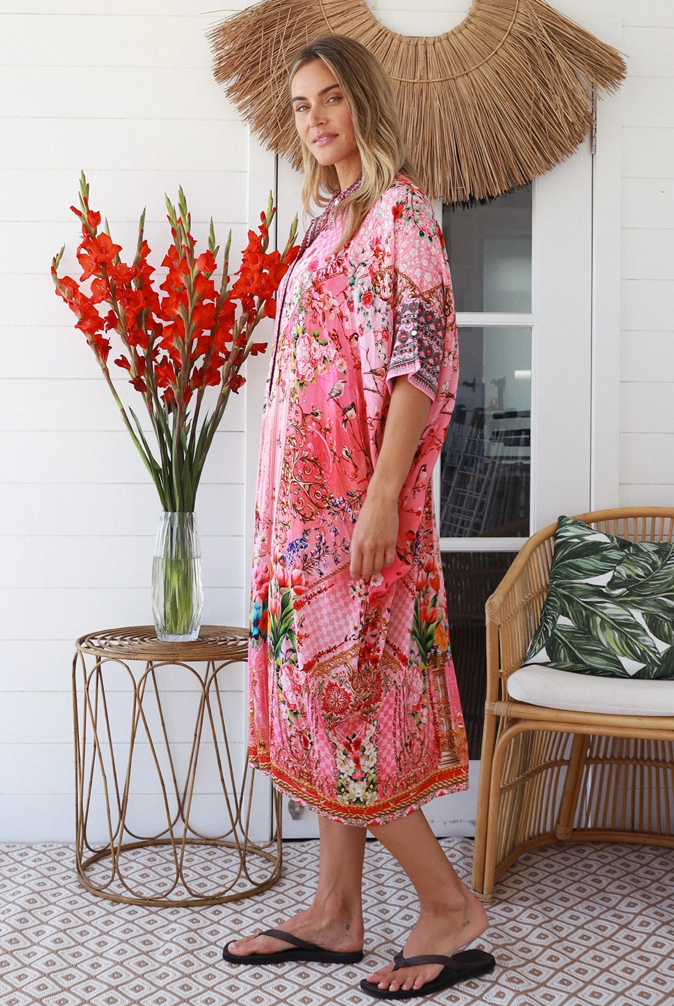 “Woman in pink floral viscose crepe kaftan midi dress with rhinestone buttons by Peacock Feathers – bohemian resort wear Australia”