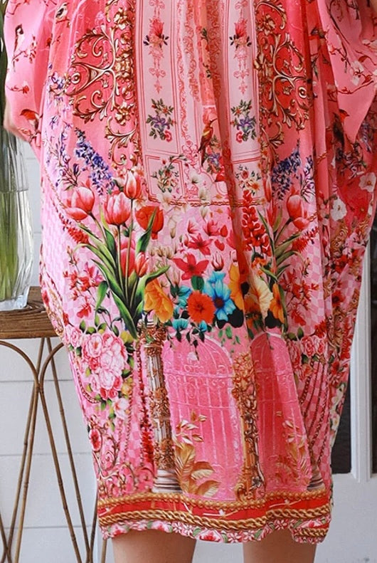 “Woman in pink floral viscose crepe kaftan midi dress with rhinestone buttons by Peacock Feathers – bohemian resort wear Australia”