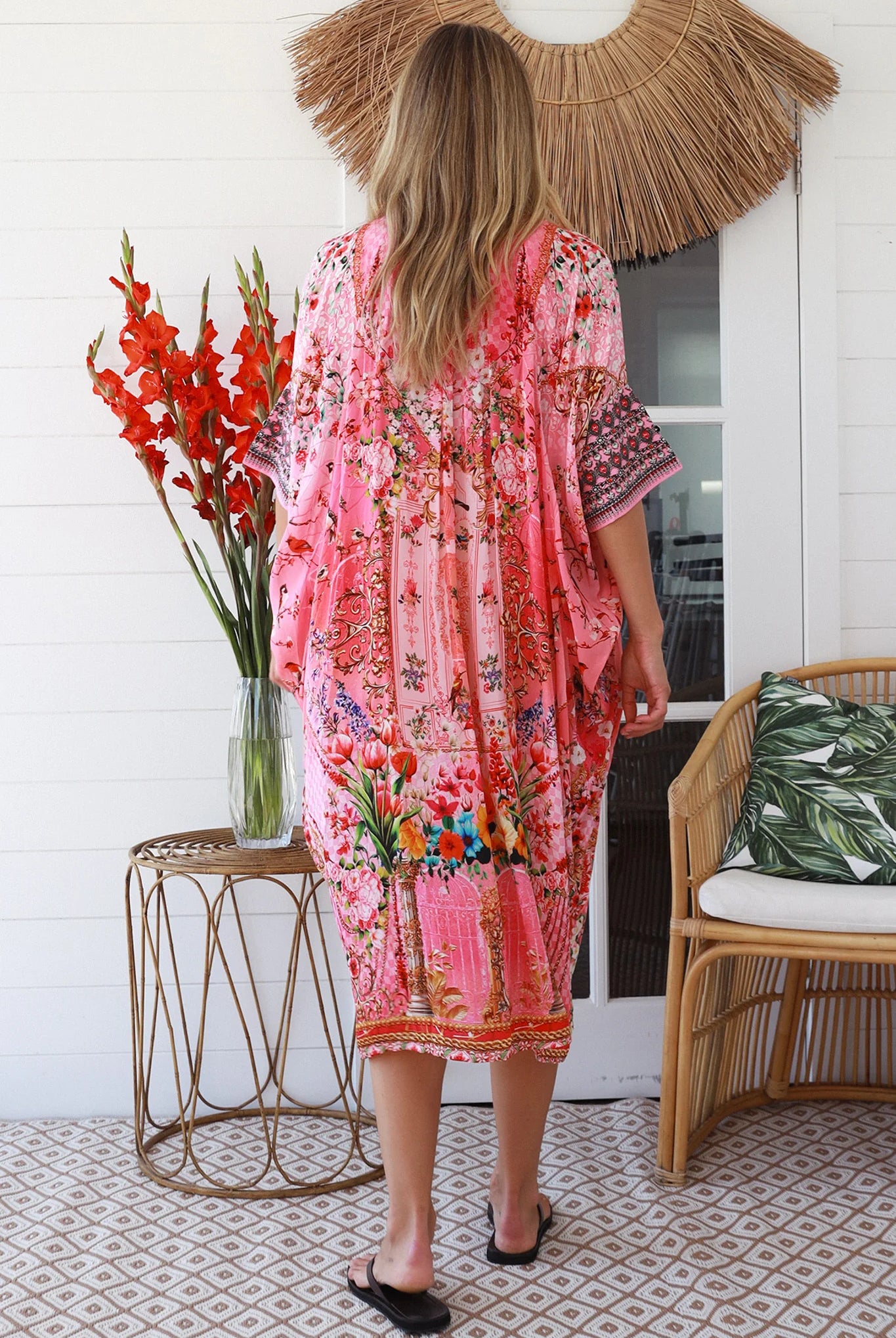 “Woman in pink floral viscose crepe kaftan midi dress with rhinestone buttons by Peacock Feathers – bohemian resort wear Australia”