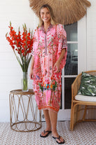 “Woman in pink floral viscose crepe kaftan midi dress with rhinestone buttons by Peacock Feathers – bohemian resort wear Australia”