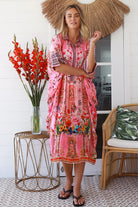 “Woman in pink floral viscose crepe kaftan midi dress with rhinestone buttons by Peacock Feathers – bohemian resort wear Australia”