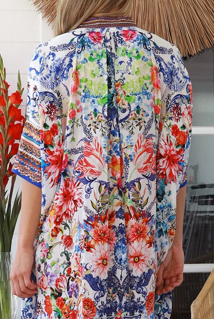 Woman in white viscose crepe kaftan midi dress with coral, jade and cobalt florals by Peacock Feathers Resort Luxe – Boho Dresses Australia