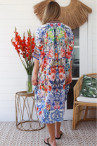Woman in white viscose crepe kaftan midi dress with coral, jade and cobalt florals by Peacock Feathers Resort Luxe – Boho Dresses Australia