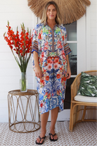 Woman in white viscose crepe kaftan midi dress with coral, jade and cobalt florals by Peacock Feathers Resort Luxe – Boho Dresses Australia