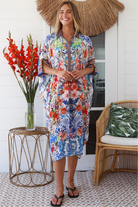 Woman in white viscose crepe kaftan midi dress with coral, jade and cobalt florals by Peacock Feathers Resort Luxe – Boho Dresses Australia