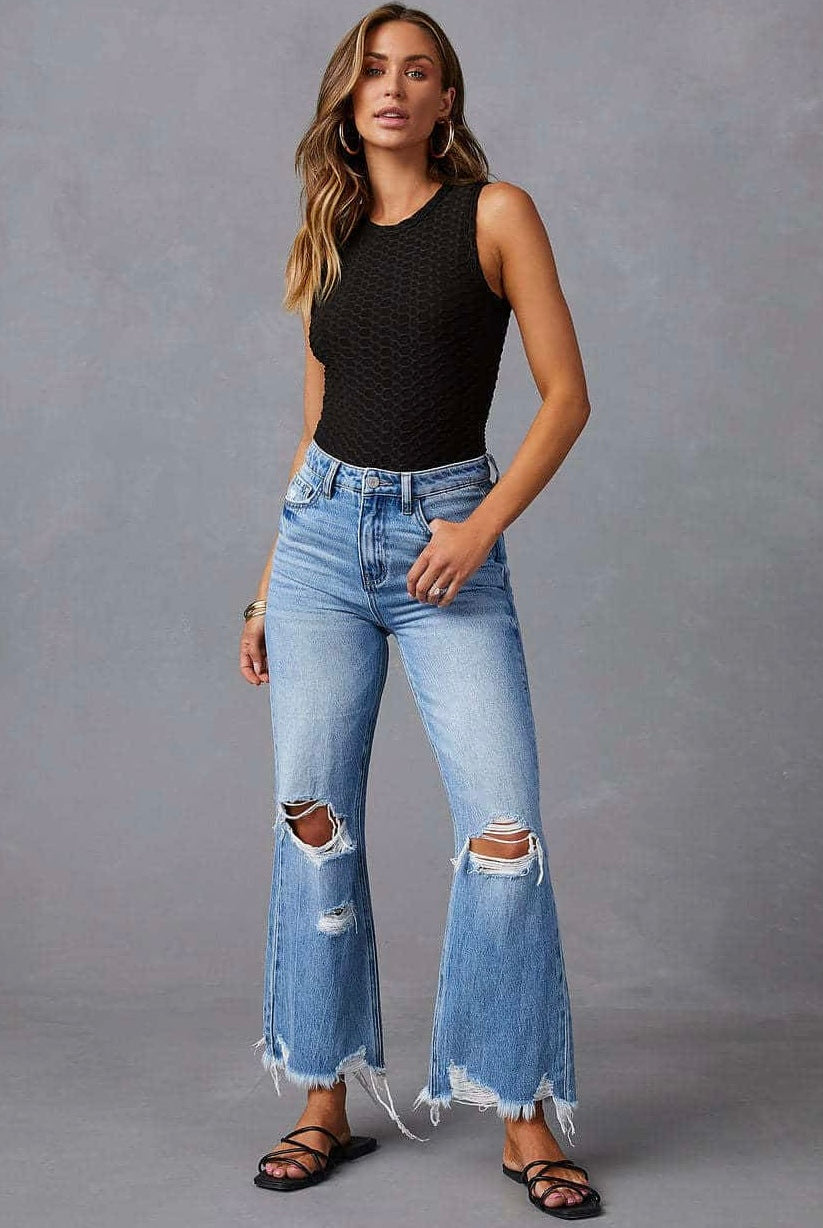 Woman wearing high-waisted light blue wide-leg jeans with raw hem and black tank - boho denim jeans Australia.