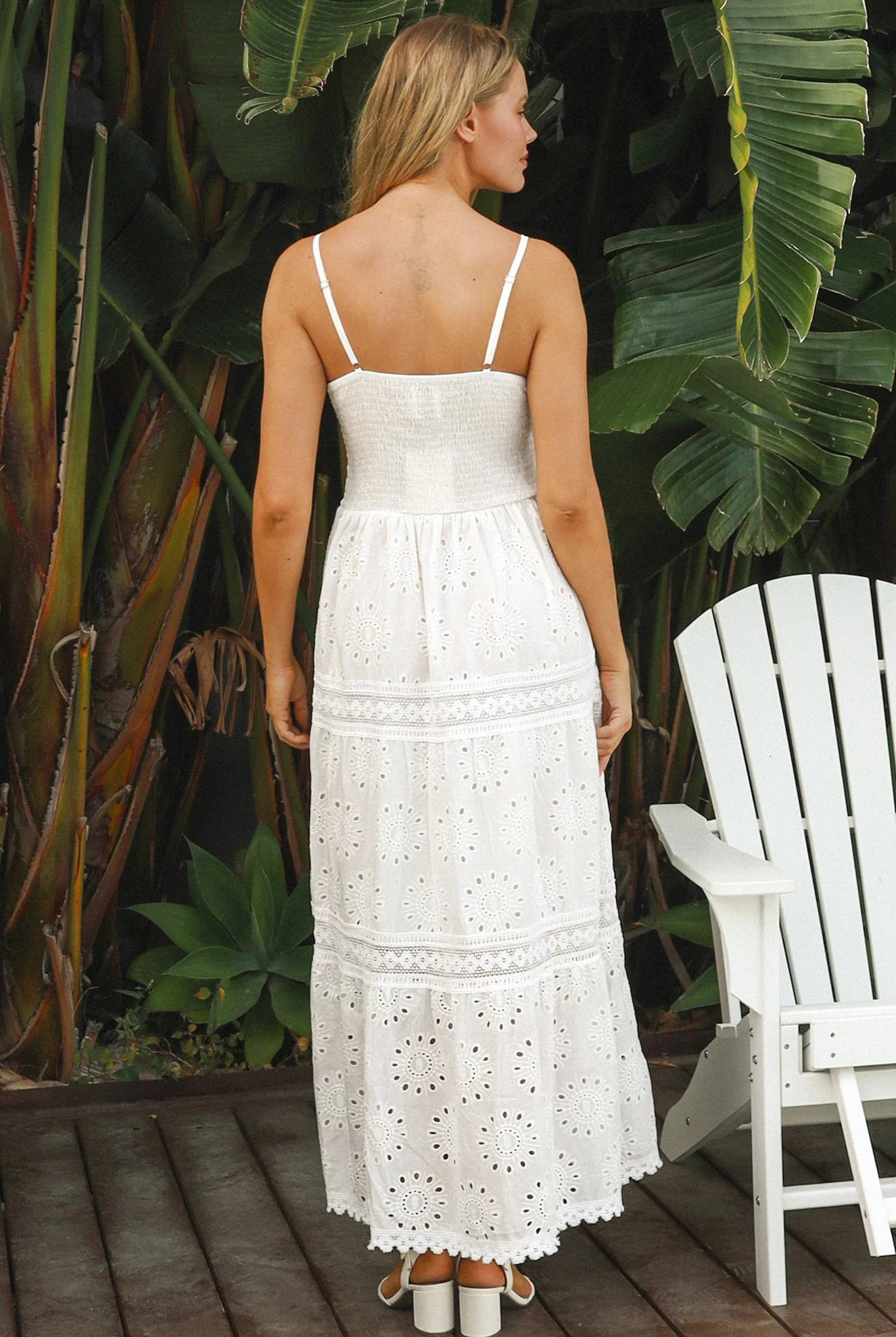 White embroidered cotton maxi dress with lace-trim neckline and scalloped tiered skirt in natural summer light.