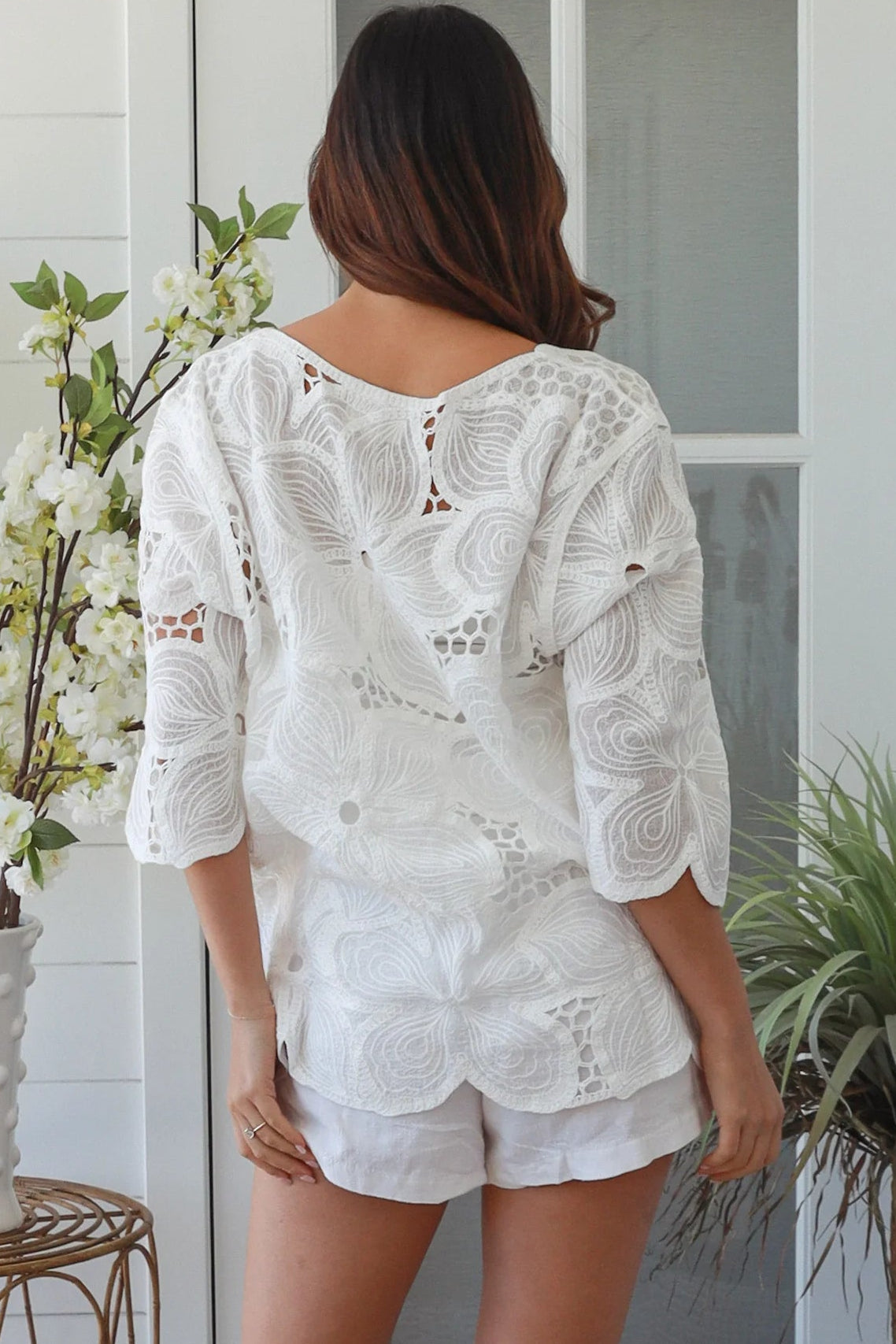 White embroidered cotton top with scalloped hem and three quarter sleeves styled for summer