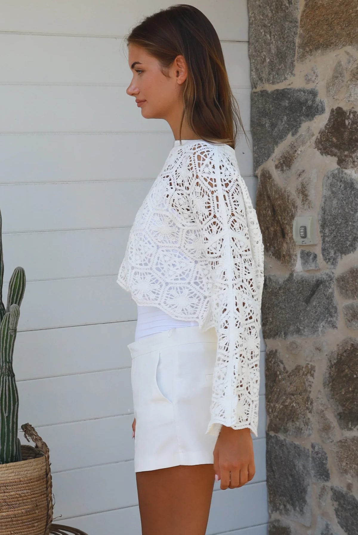 Woman wearing white crochet cotton boho top with long sleeves styled with white shorts Australian fashion