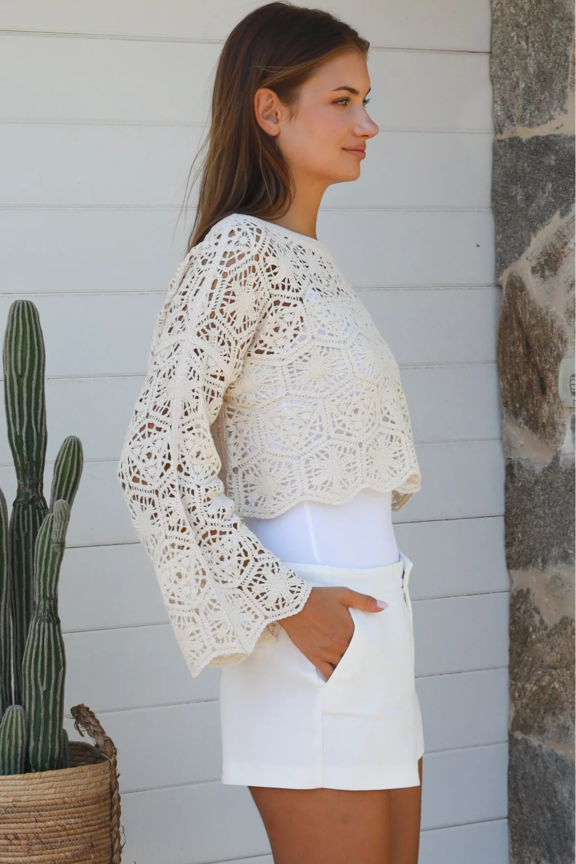 Cream crochet cotton long sleeve crop top with scalloped hem and flared cuffs styled with white shorts