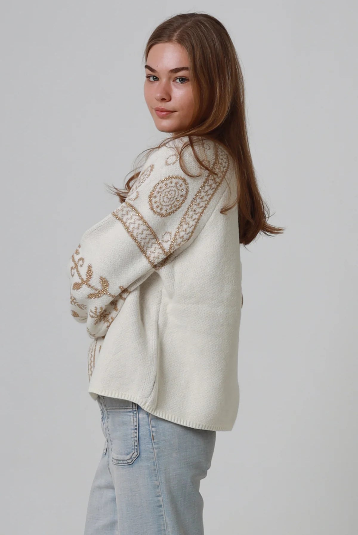 Woman wearing cream boho knit jumper with golden lurex detailing, balloon sleeves and relaxed winter styling.