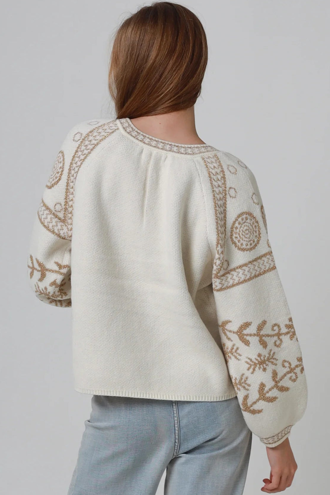 Woman wearing cream boho knit jumper with golden lurex detailing, balloon sleeves and relaxed winter styling.
