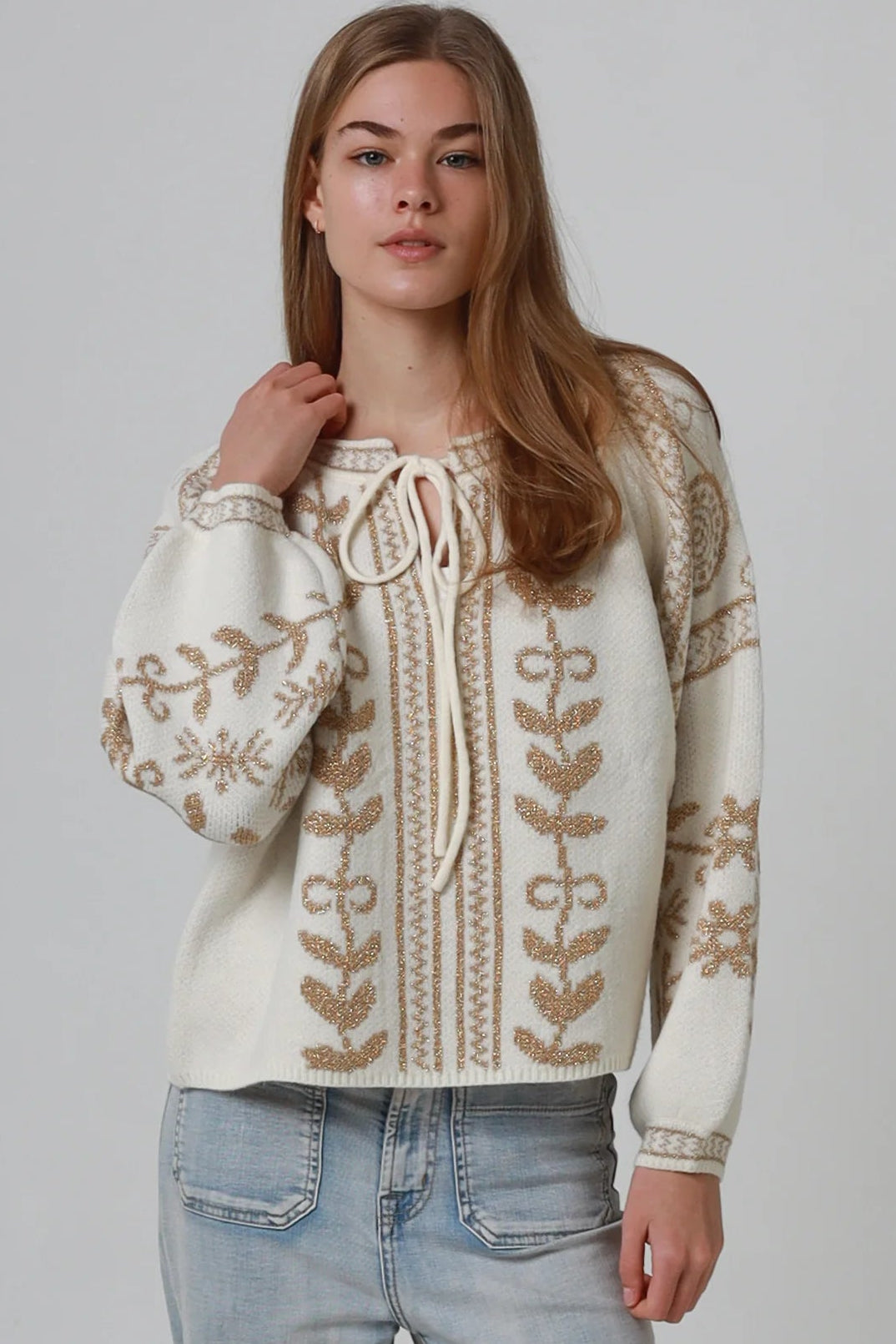Woman wearing cream boho knit jumper with golden lurex detailing, balloon sleeves and relaxed winter styling.