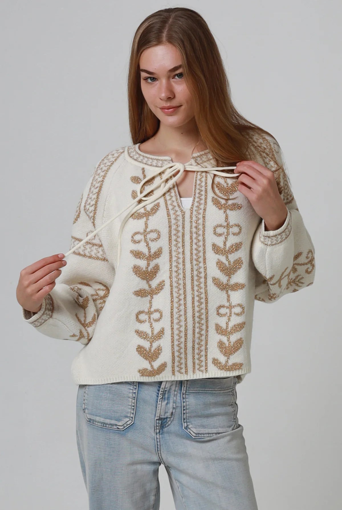 Woman wearing cream boho knit jumper with golden lurex detailing, balloon sleeves and relaxed winter styling.