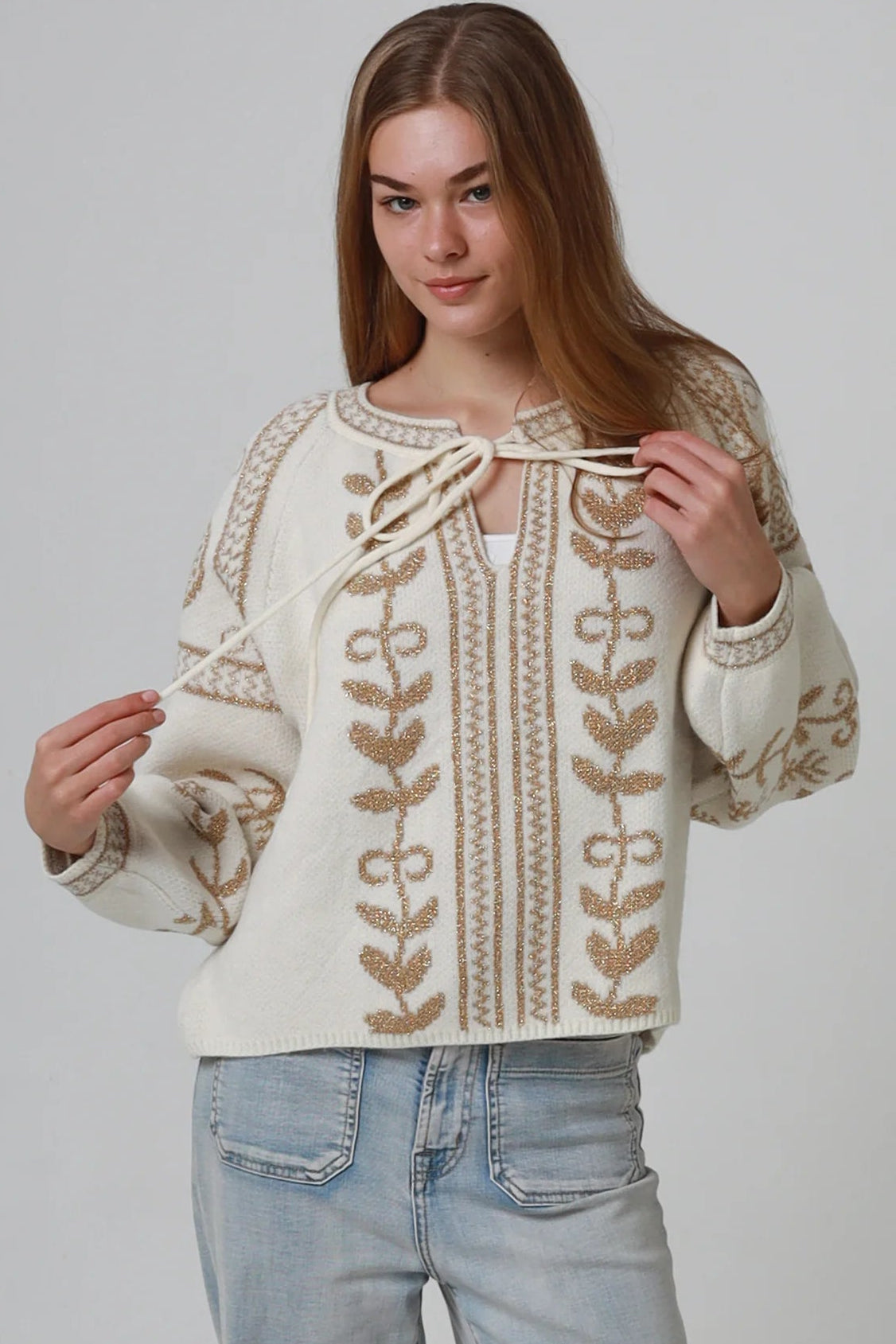 Woman wearing cream boho knit jumper with golden lurex detailing, balloon sleeves and relaxed winter styling.