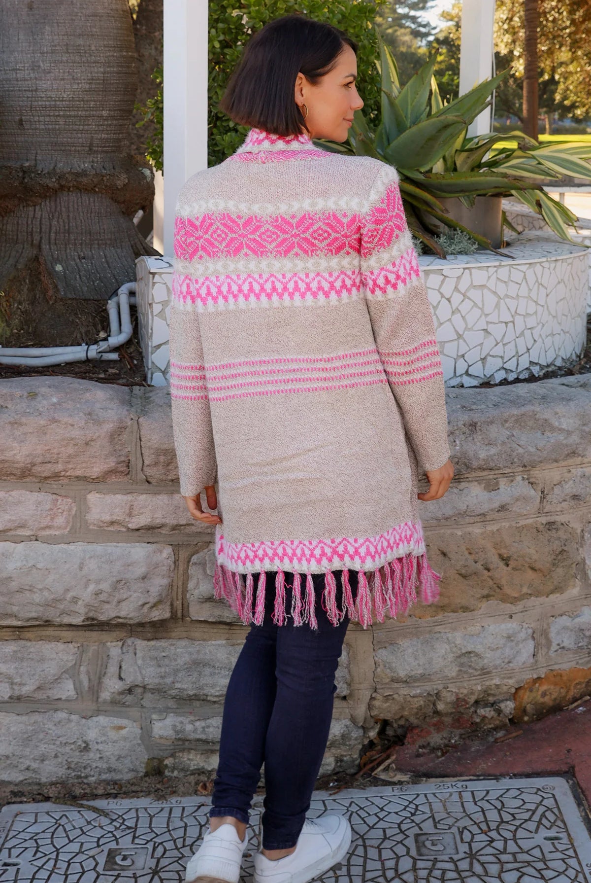 Woman wearing longline rose pink and cream boho knit cardigan with fringe hem - Australian winter fashion.