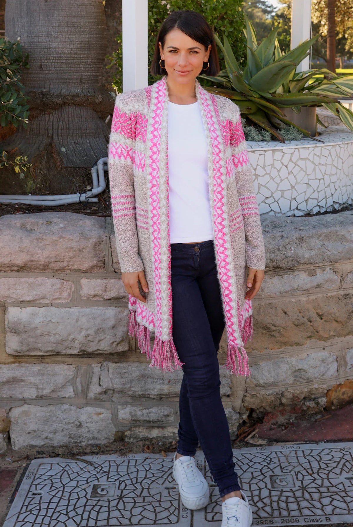 Woman wearing longline rose pink and cream boho knit cardigan with fringe hem - Australian winter fashion.