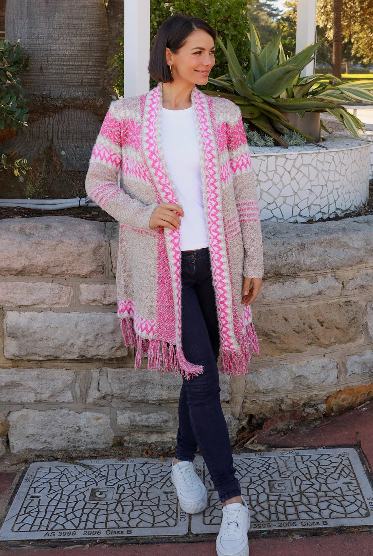Woman wearing longline rose pink and cream boho knit cardigan with fringe hem - Australian winter fashion.