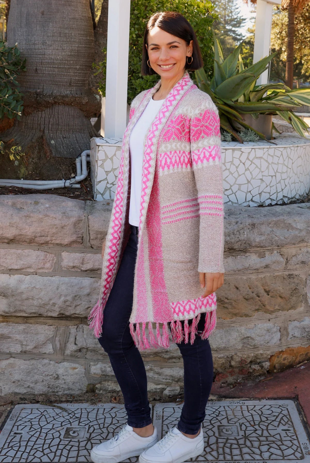 Woman wearing longline rose pink and cream boho knit cardigan with fringe hem - Australian winter fashion.