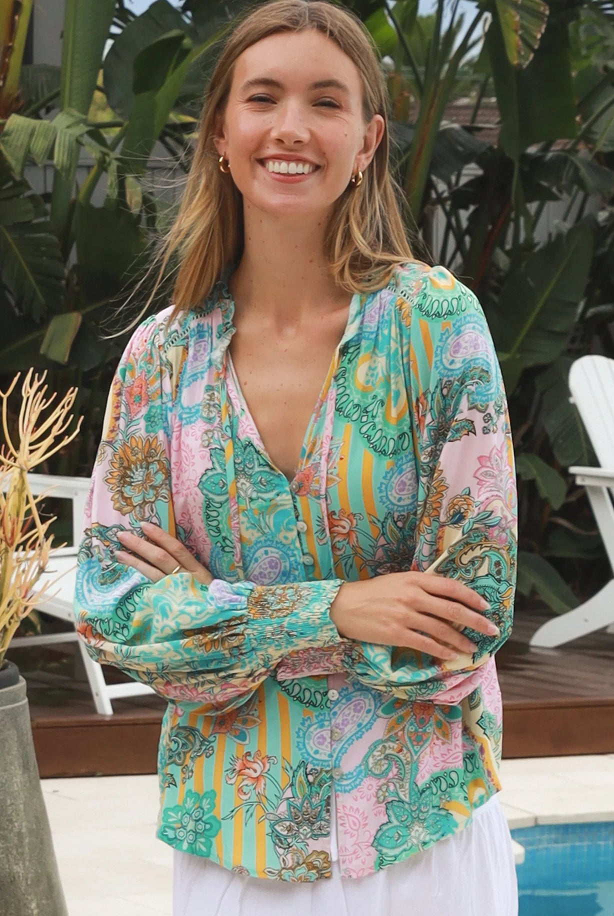 Woman wearing Salty Palm Mika Blouse in green patchwork rayon with V-neck tie, cotton lace shoulders and crochet yoke
