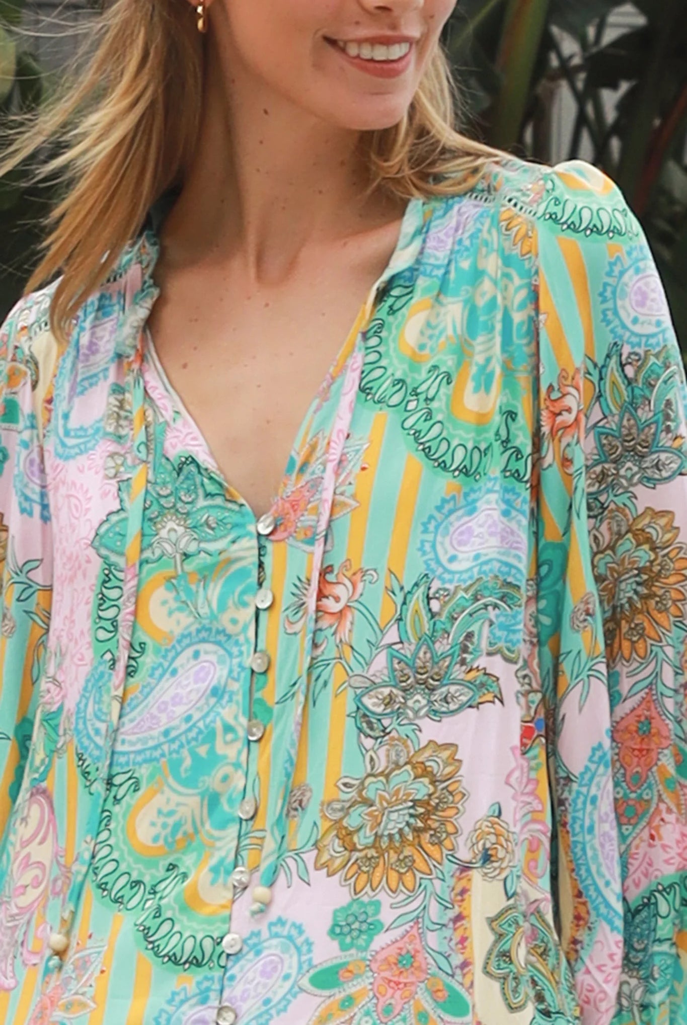 Woman wearing Salty Palm Mika Blouse in green patchwork rayon with V-neck tie, cotton lace shoulders and crochet yoke