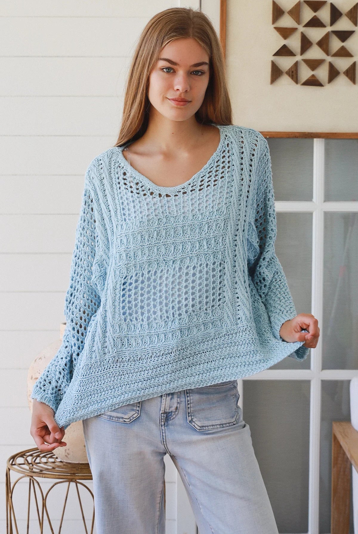 Woman wearing pastel blue crochet knit sweater styled with denim for a refined boho winter outfit Australia
