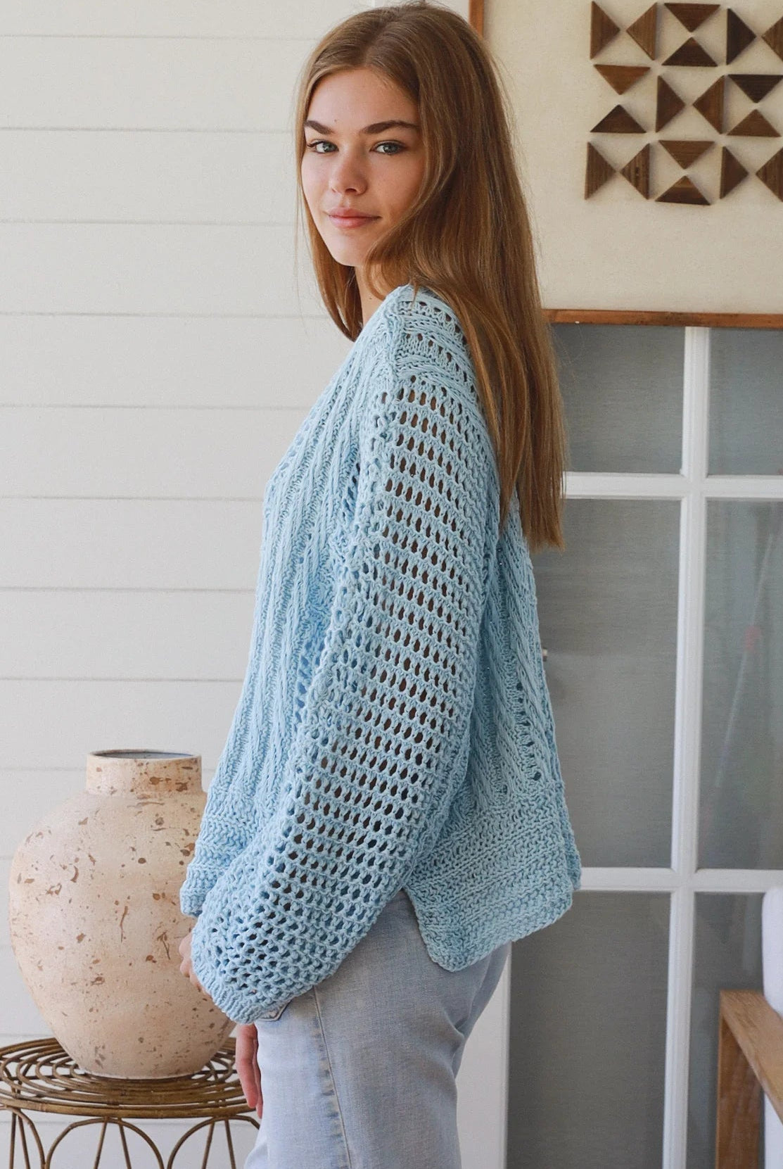 Woman wearing pastel blue crochet knit sweater styled with denim for a refined boho winter outfit Australia
