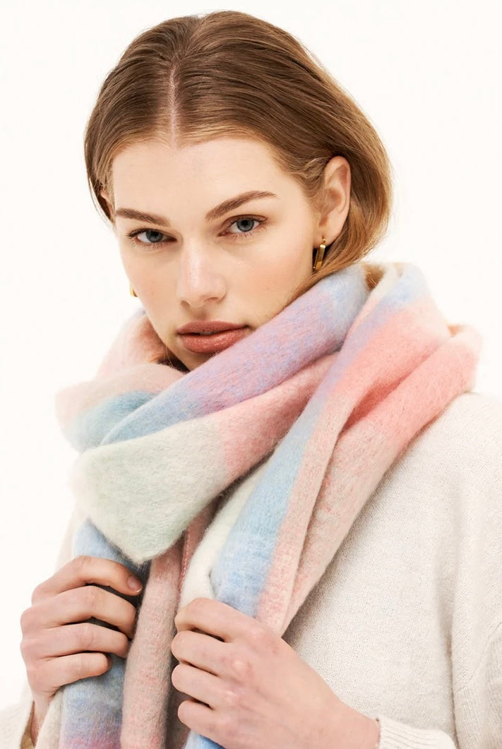Woman in a pastel check boho winter scarf with blush, blue, and cream tones and long tassels - The Aurielle Scarf by Bohemian Love Runway