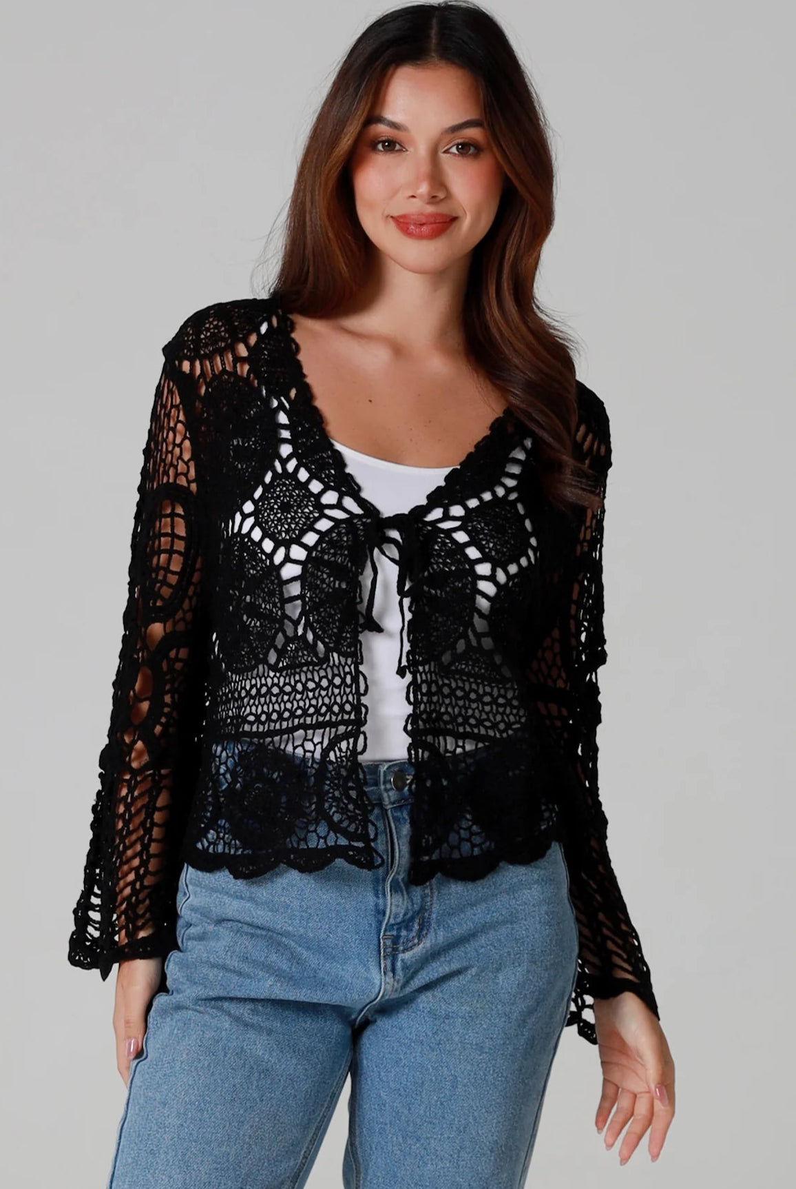 Woman in black 100% cotton crochet top with bell sleeves and tie front - one size boho top styled with denim