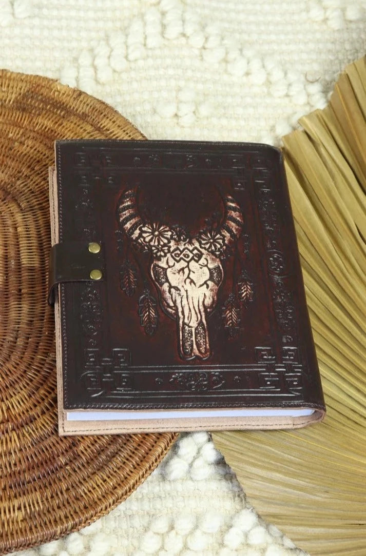 Dark leather journal with hand-tooled bull skull design on woven mat - Gypsy Toro boho journal from Bohemian Love Runway
