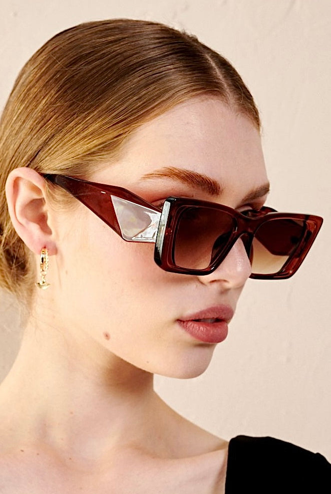 Woman in brown oversized cat eye sunglasses with sleek bun and black top - vintage boho style Australia.