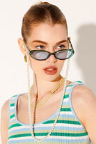 woman in green retro oval sunglasses with striped top and gold chain - playful vintage boho summer style Australia.