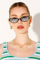 woman in green retro oval sunglasses with striped top and gold chain - playful vintage boho summer style Australia.