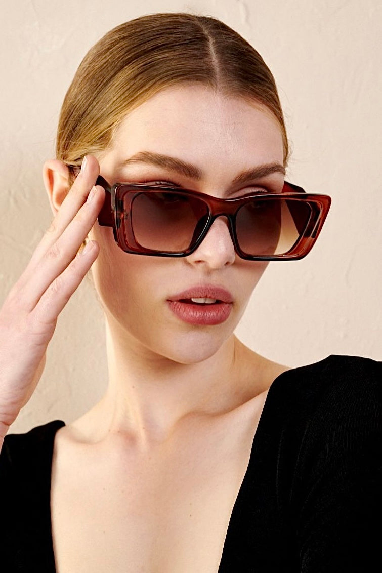 Woman in brown oversized cat eye sunglasses with sleek bun and black top - vintage boho style Australia.