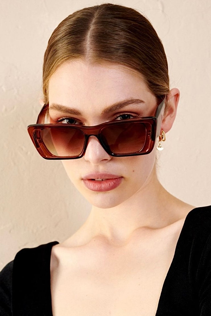 Woman in brown oversized cat eye sunglasses with sleek bun and black top - vintage boho style Australia.