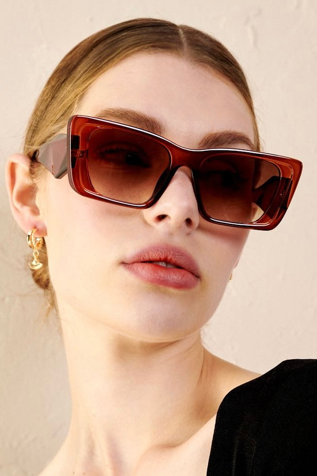 Woman in brown oversized cat eye sunglasses with sleek bun and black top - vintage boho style Australia.