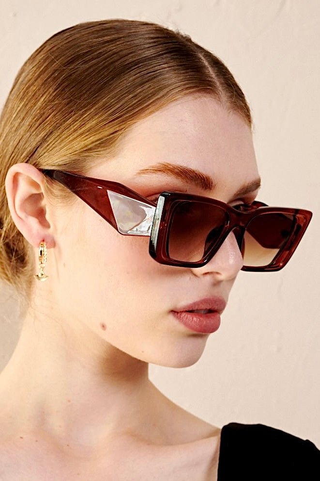 Woman in brown oversized cat eye sunglasses with sleek bun and black top - vintage boho style Australia.