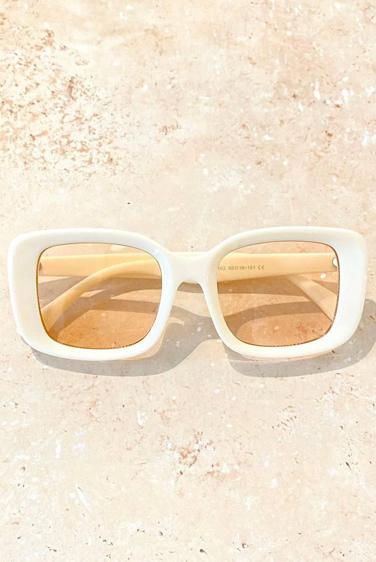 Woman in a white retro square sunglasses and red top with soft waves - bold boho fashion statement Australia.