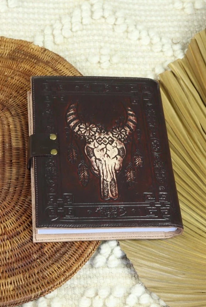 Dark leather journal with hand-tooled bull skull design on woven mat - Gypsy Toro boho journal from Bohemian Love Runway
