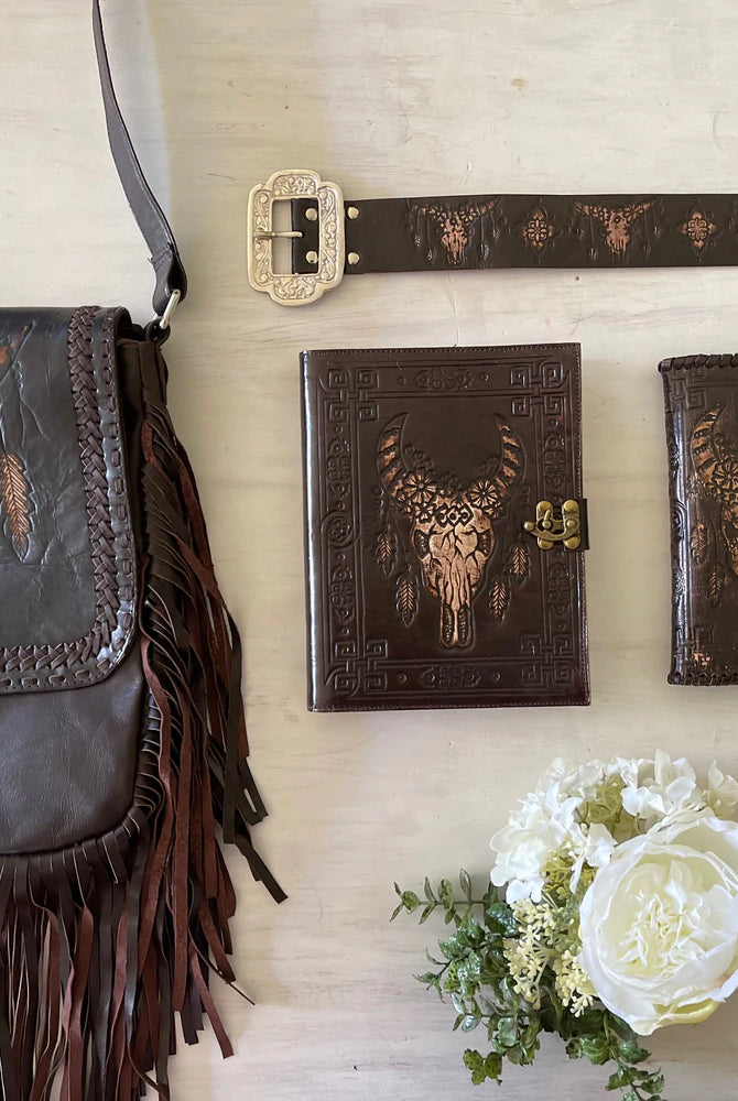 Dark leather journal with hand-tooled bull skull design on woven mat - Gypsy Toro boho journal from Bohemian Love Runway
