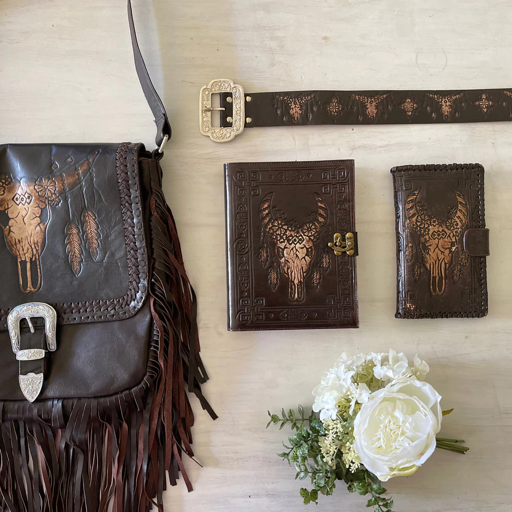 Dark leather journal with hand-tooled bull skull design on woven mat - Gypsy Toro boho journal from Bohemian Love Runway