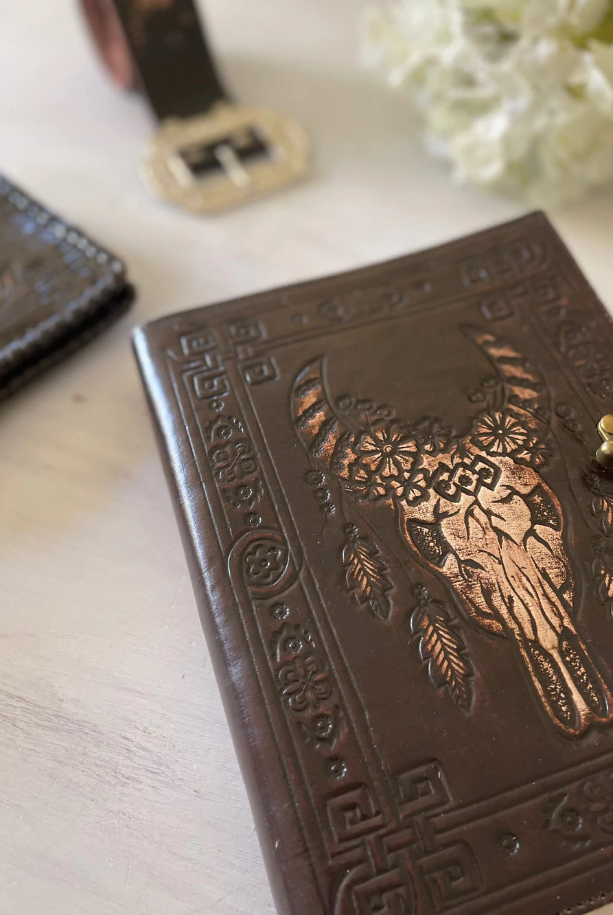 Dark leather journal with hand-tooled bull skull design on woven mat - Gypsy Toro boho journal from Bohemian Love Runway